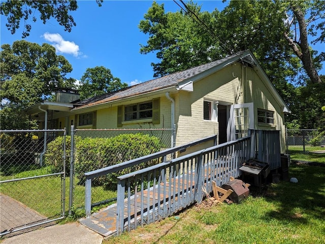 view of home's exterior with brick siding, a lawn, fence, and a gate