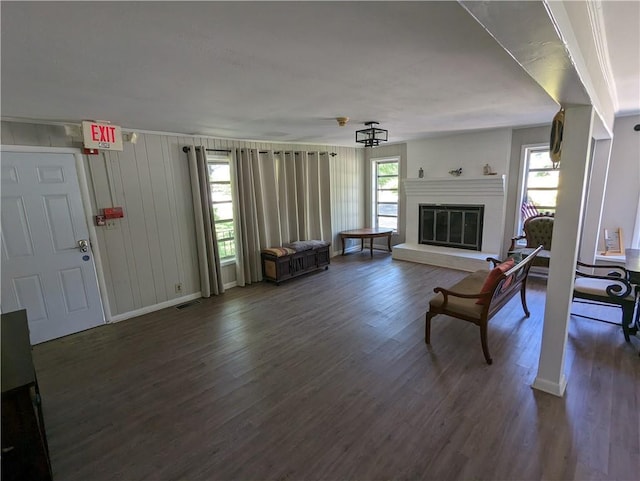 living area featuring visible vents, baseboards, dark wood finished floors, and a glass covered fireplace