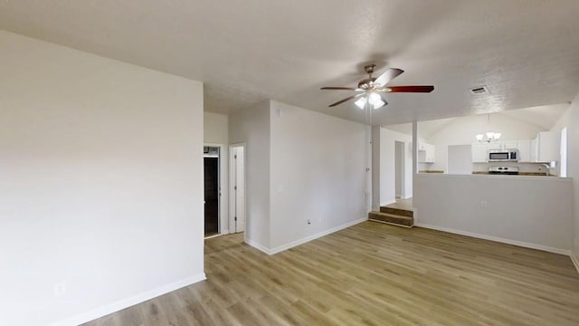 unfurnished living room with visible vents, baseboards, lofted ceiling, light wood-style floors, and ceiling fan with notable chandelier