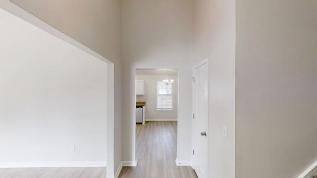 hall with light wood-style flooring and baseboards