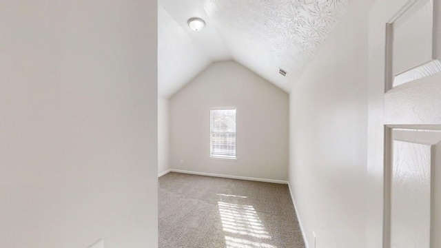 bonus room featuring carpet, visible vents, baseboards, vaulted ceiling, and a textured ceiling