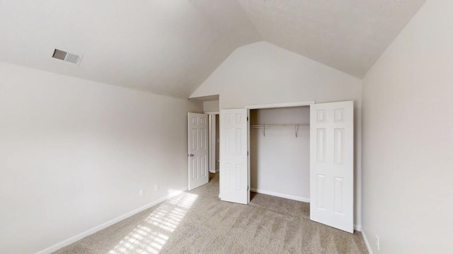 unfurnished bedroom featuring visible vents, lofted ceiling, light colored carpet, and baseboards