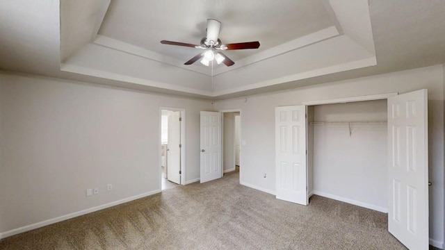 unfurnished bedroom featuring baseboards, a raised ceiling, carpet floors, and a closet