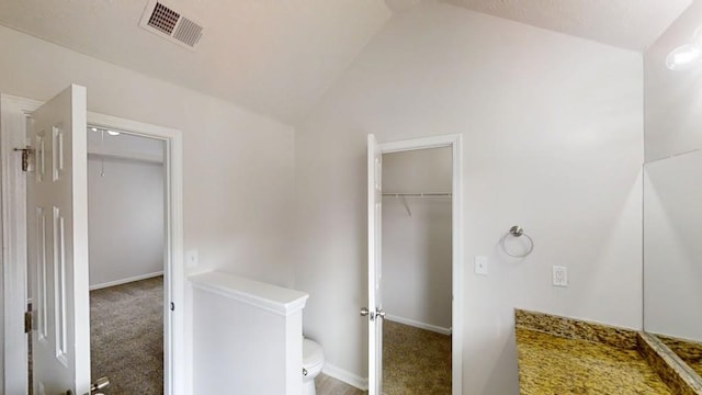 bathroom featuring vaulted ceiling, toilet, baseboards, and visible vents