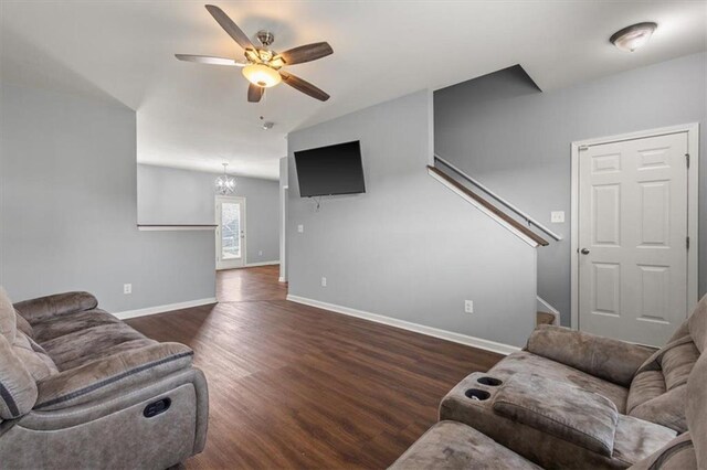 living room with ceiling fan with notable chandelier, baseboards, stairs, and wood finished floors