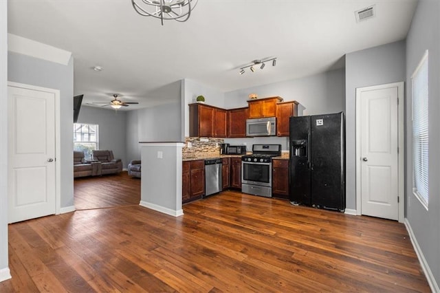 kitchen with ceiling fan, appliances with stainless steel finishes, dark hardwood / wood-style floors, light stone counters, and decorative backsplash