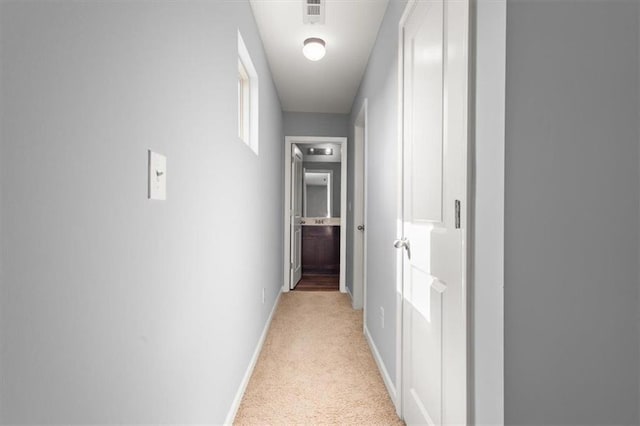 hall with light colored carpet, visible vents, and baseboards