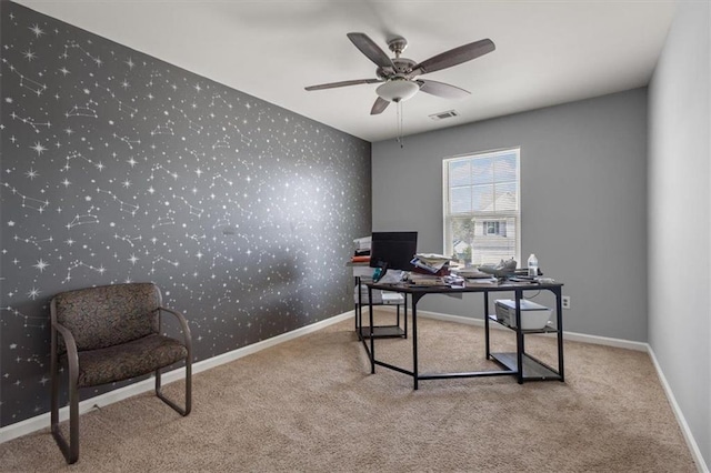 carpeted office featuring baseboards, ceiling fan, visible vents, and wallpapered walls
