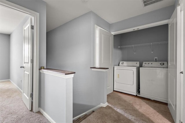 clothes washing area with light carpet and washer and clothes dryer