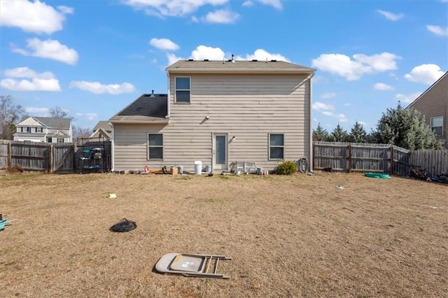 rear view of property with a fenced backyard and a lawn