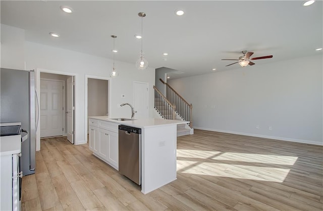 kitchen featuring appliances with stainless steel finishes, light wood-type flooring, light countertops, and a sink