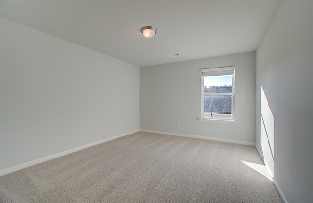 spare room with light carpet, visible vents, and baseboards