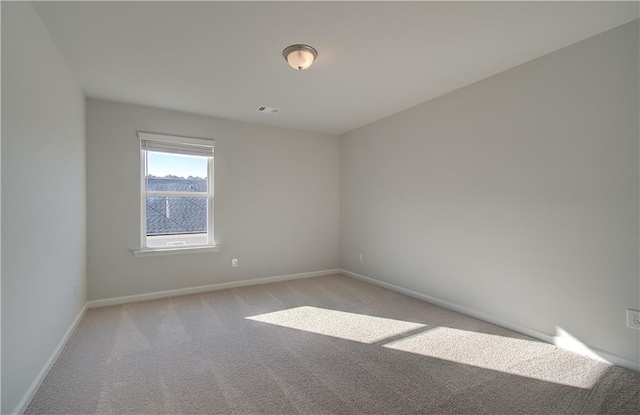 unfurnished room featuring light carpet and baseboards