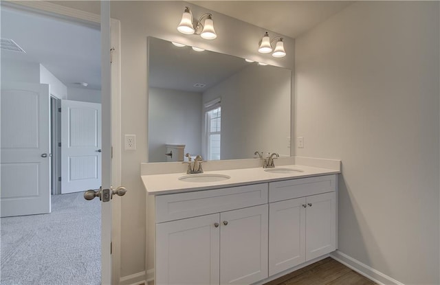 bathroom featuring double vanity, a sink, visible vents, and baseboards