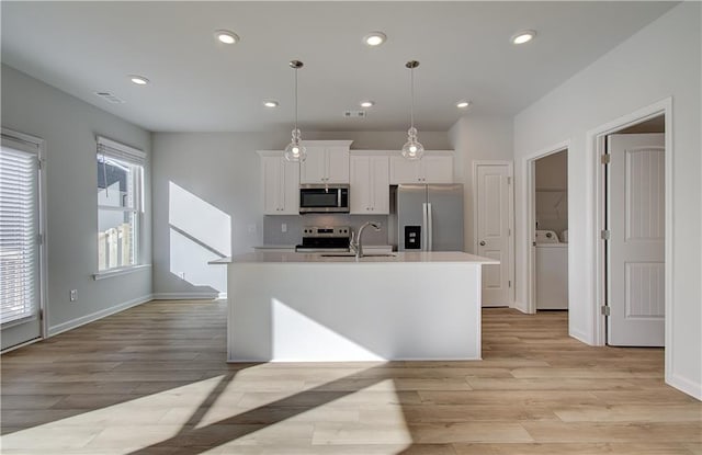 kitchen featuring white cabinets, light wood-style flooring, a kitchen island with sink, stainless steel appliances, and light countertops