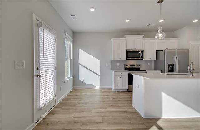 kitchen with appliances with stainless steel finishes, a sink, visible vents, and white cabinets