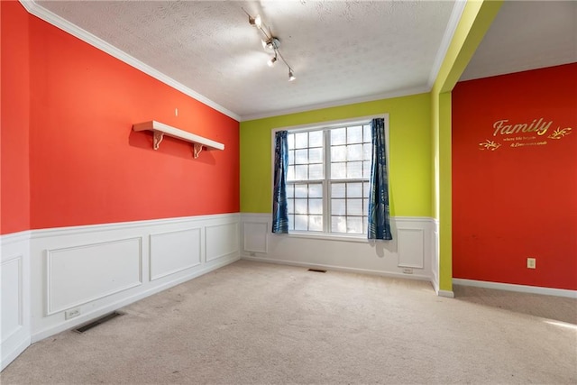 unfurnished room with rail lighting, light carpet, ornamental molding, and a textured ceiling