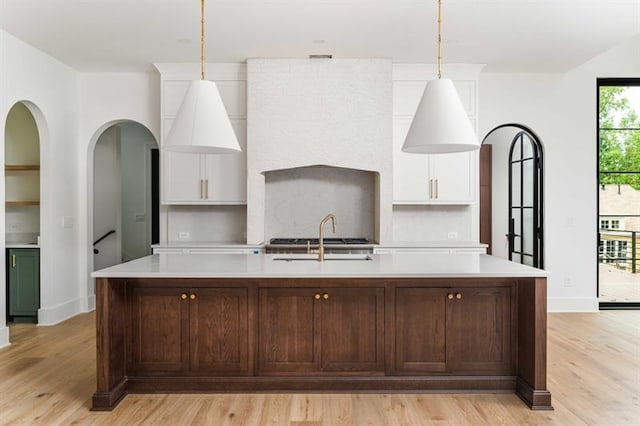 kitchen featuring sink, pendant lighting, a center island with sink, and light wood-type flooring