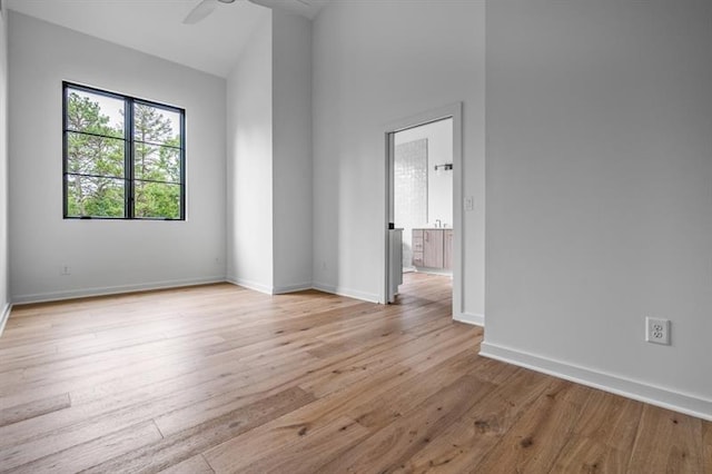 spare room with light wood-type flooring, high vaulted ceiling, and ceiling fan