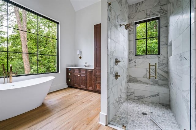 bathroom featuring hardwood / wood-style floors, vanity, independent shower and bath, and vaulted ceiling