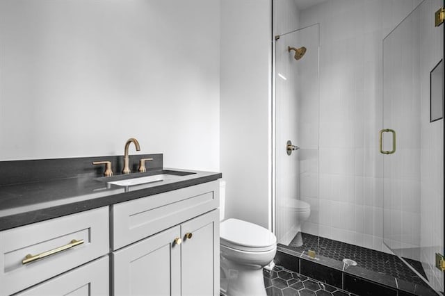 bathroom featuring vanity, a shower with shower door, and toilet