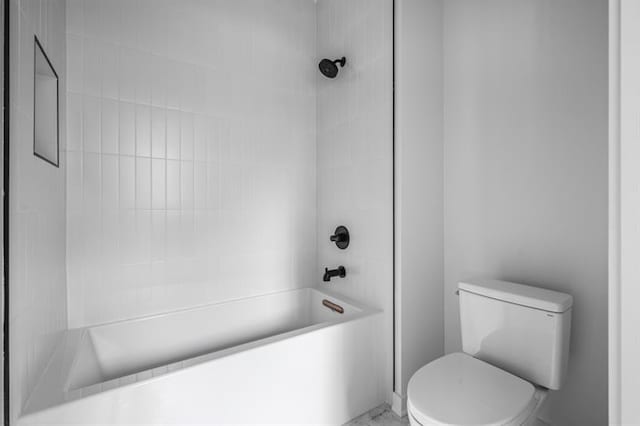 bathroom featuring toilet and tiled shower / bath