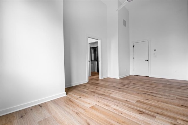 unfurnished room featuring light hardwood / wood-style flooring and a high ceiling