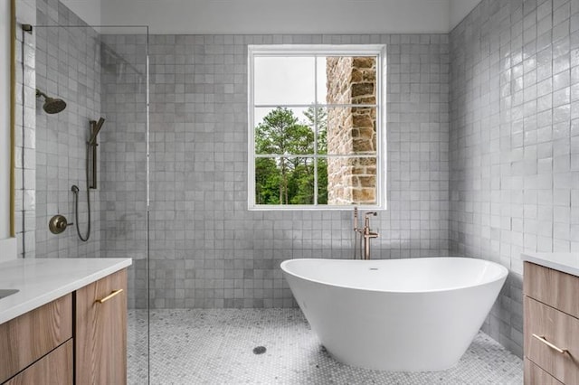 bathroom with tile patterned flooring, vanity, tile walls, and plus walk in shower