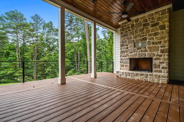 wooden terrace featuring ceiling fan and an outdoor stone fireplace