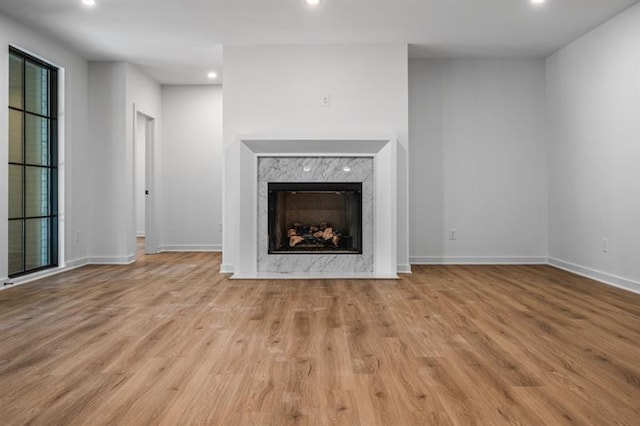 unfurnished living room featuring a high end fireplace and light wood-type flooring