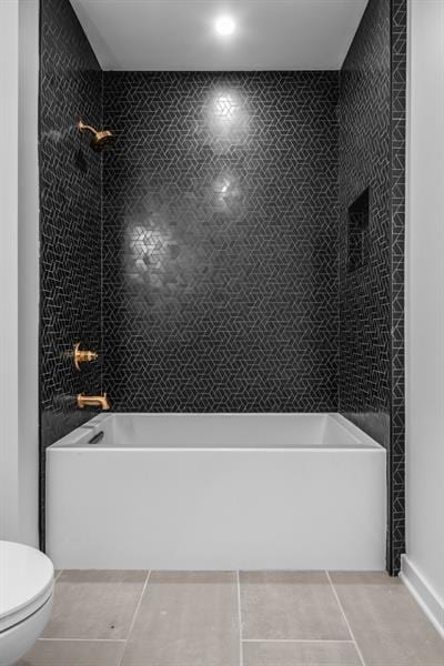 bathroom featuring tile patterned flooring, toilet, tiled shower / bath, and tile walls