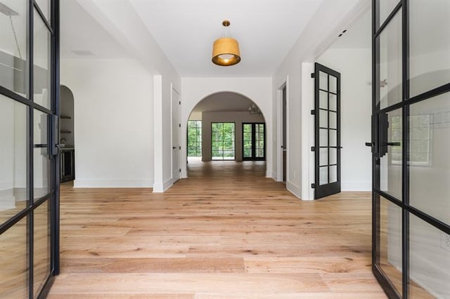 corridor with light hardwood / wood-style floors and french doors