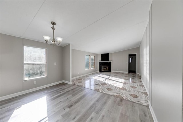 unfurnished living room with a chandelier, vaulted ceiling, and light hardwood / wood-style floors