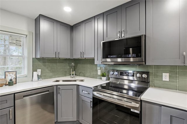 kitchen with sink, backsplash, gray cabinets, and appliances with stainless steel finishes