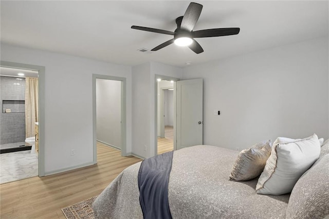 bedroom featuring ceiling fan, light wood-type flooring, and ensuite bath