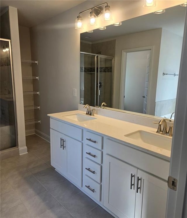 bathroom featuring double vanity, a stall shower, a sink, and tile patterned floors