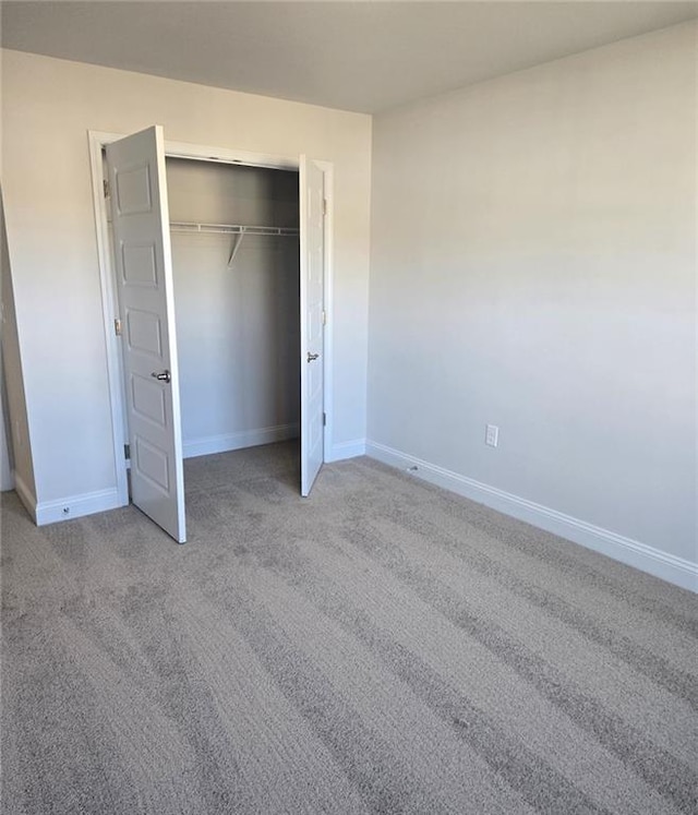 unfurnished bedroom featuring light carpet, a closet, and baseboards