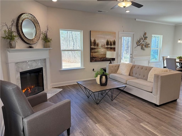 living room with visible vents, ornamental molding, wood finished floors, a fireplace, and ceiling fan