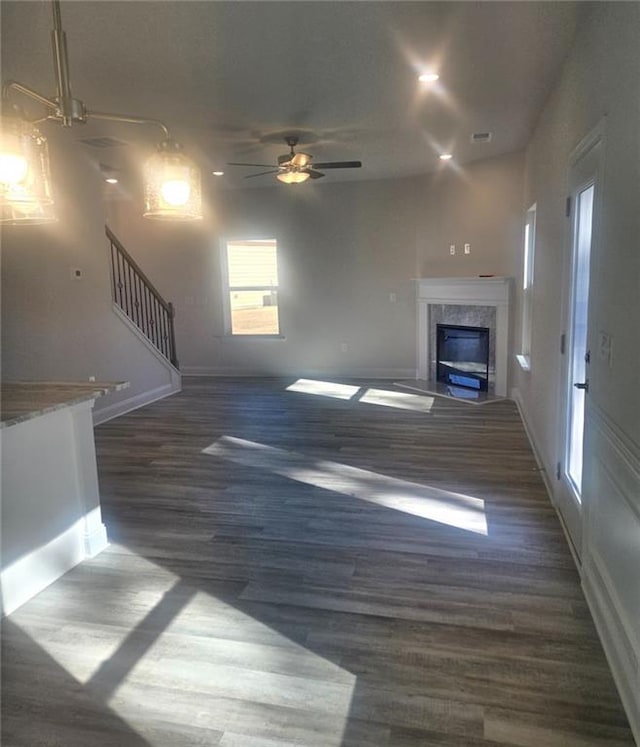 unfurnished living room with recessed lighting, a premium fireplace, ceiling fan, wood finished floors, and stairs