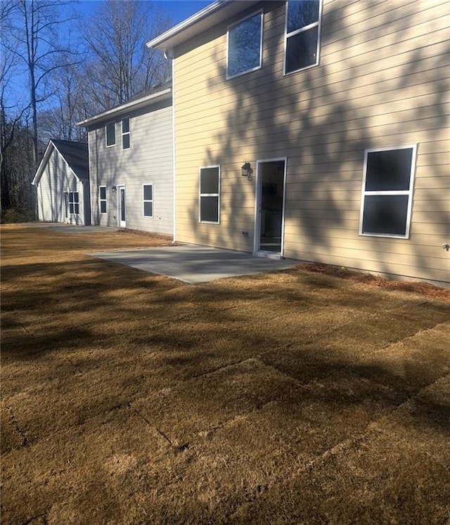 rear view of property featuring a lawn and a patio area