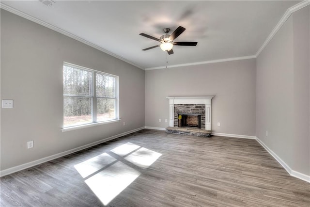 unfurnished living room with hardwood / wood-style floors, a stone fireplace, ceiling fan, and ornamental molding