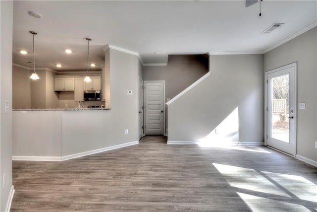 unfurnished living room featuring light wood-type flooring, crown molding, and a wealth of natural light