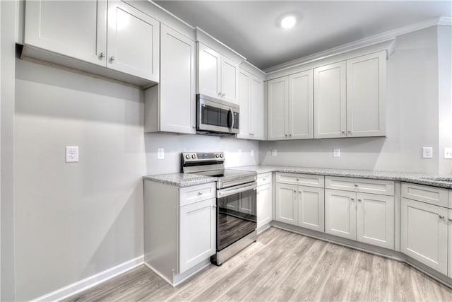 kitchen featuring white cabinets, light stone counters, appliances with stainless steel finishes, and light hardwood / wood-style flooring