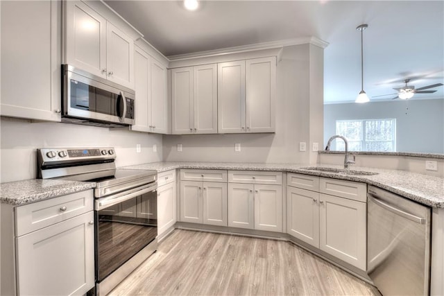 kitchen featuring light stone countertops, stainless steel appliances, sink, decorative light fixtures, and white cabinets