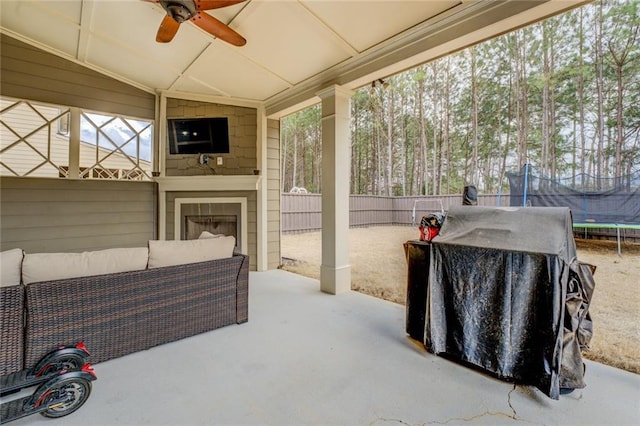 view of patio with ceiling fan, grilling area, a trampoline, fence, and an outdoor living space