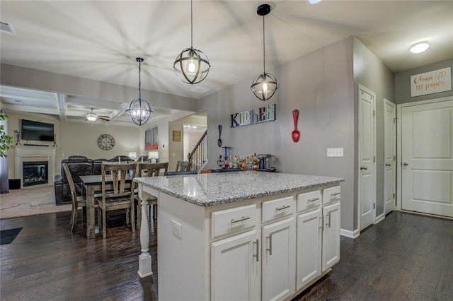 kitchen with dark wood finished floors, a glass covered fireplace, open floor plan, white cabinetry, and coffered ceiling