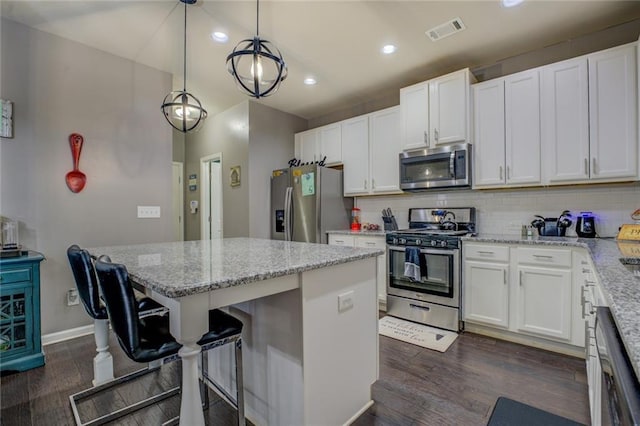 kitchen featuring visible vents, white cabinets, appliances with stainless steel finishes, backsplash, and a center island