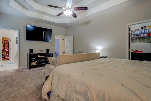 carpeted bedroom featuring a closet, a raised ceiling, a spacious closet, a ceiling fan, and baseboards