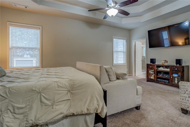 carpeted bedroom with ornamental molding, a raised ceiling, visible vents, and ceiling fan