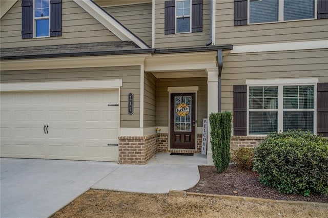 entrance to property with a garage, concrete driveway, and brick siding